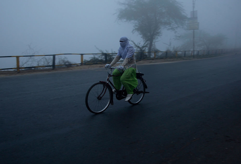 A girl cycles on a foggy and cold winter morning in the northern Indian city of Allahabad January 3, 2013. Heavy fog and a cold wave in Northern India have disrupted life in a number of cities, killing scores of homeless in the state of Uttar Pradesh...