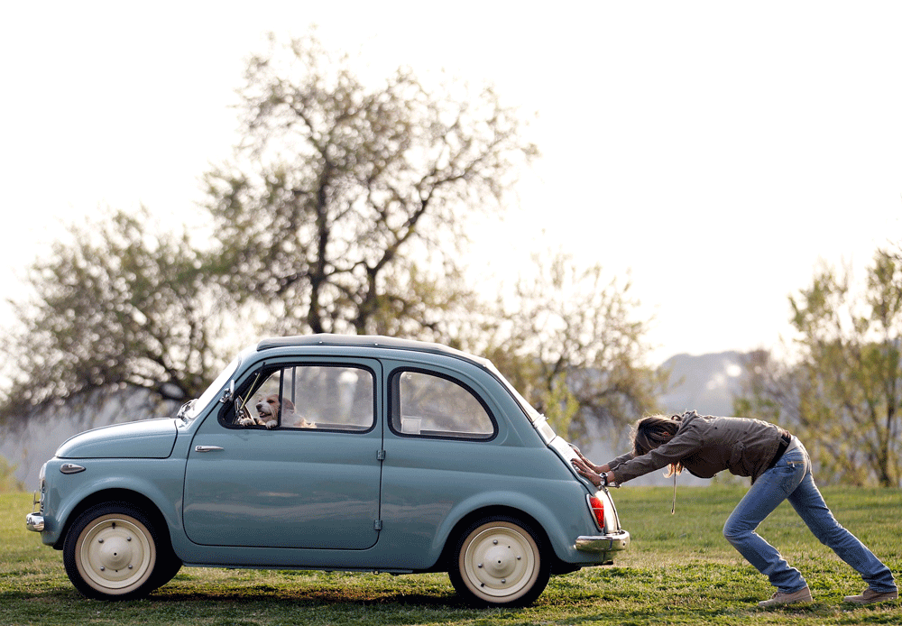 A woman pushes her Fiat 500 car as her dog sits inside, in a neighbourhood of Rome in this March 23, 2012 file photo. Regardless of who wins next weekend's parliamentary election, Italy's long economic decline is likely to continue because the next g...