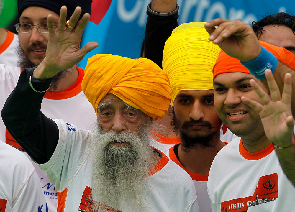 Centenarian marathon runner Fauja Singh, 101, left, originally from Beas  Pind, in Jalandhar, India but who now lives in London, waves after  finishing a 10-kilometer race, held as part of the annual Hong Kong  Marathon, in Hong Kong Sunday, Feb. 24,...