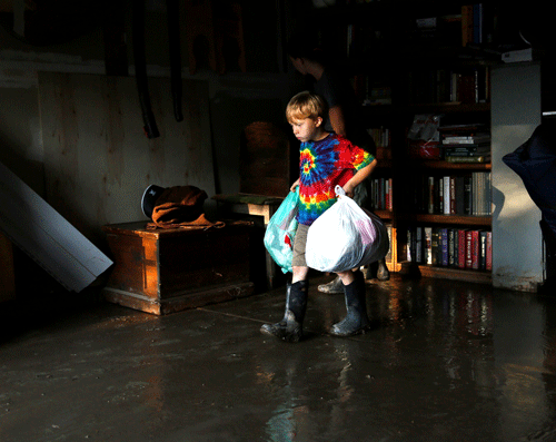 Rowen Roberson carries clothes from his flooded garage in Longmont, Colorado September 16, 2013. Seven people were confirmed dead and at least 1,500 homes destroyed in Colorado after a week of rare, torrential rains along the eastern slopes of the Ro...