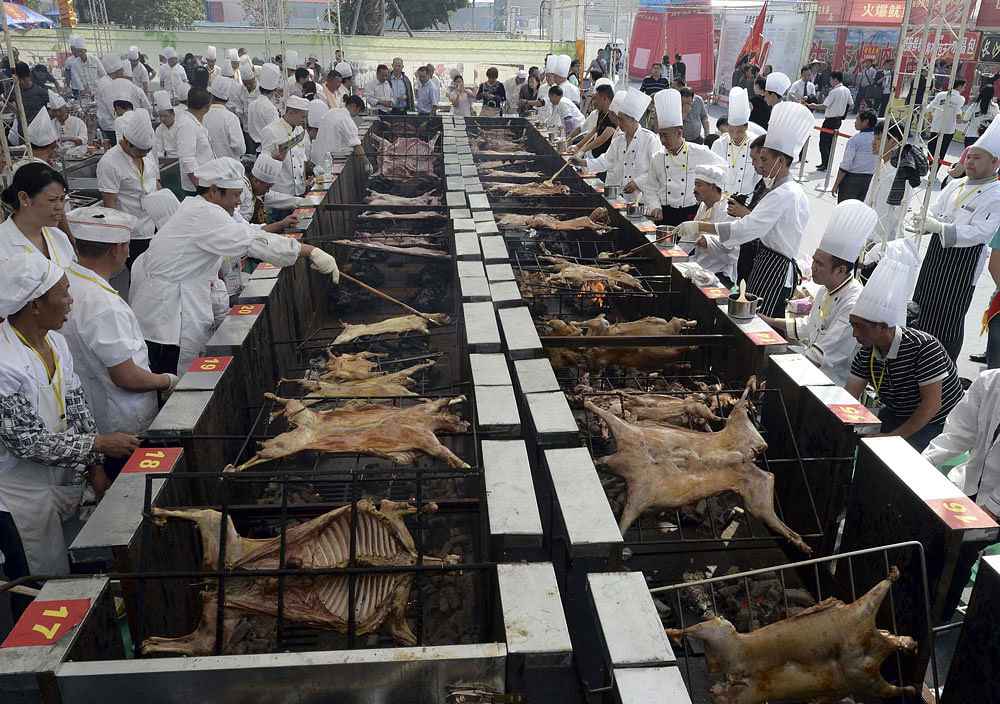 Cooks roast meat during a barbecue contest in Chongqing municipality, September 30, 2013. Over 60 barbecue experts attended the contest to compete in their skills of roasting lamb, pork, fish and chicken, among other meats, local media reported. Pict...