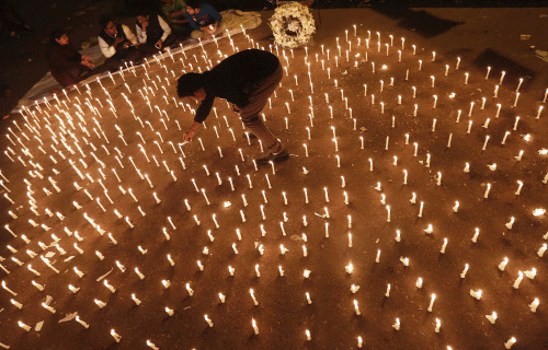 A protester lights candles during a candlelight vigil to mark the first  anniversary of the Delhi gang rape, in New Delhi December 16, 2013. A  23-year-old woman was gang-raped on a moving bus in Delhi December 16,  2012, beaten and then pushed out o...