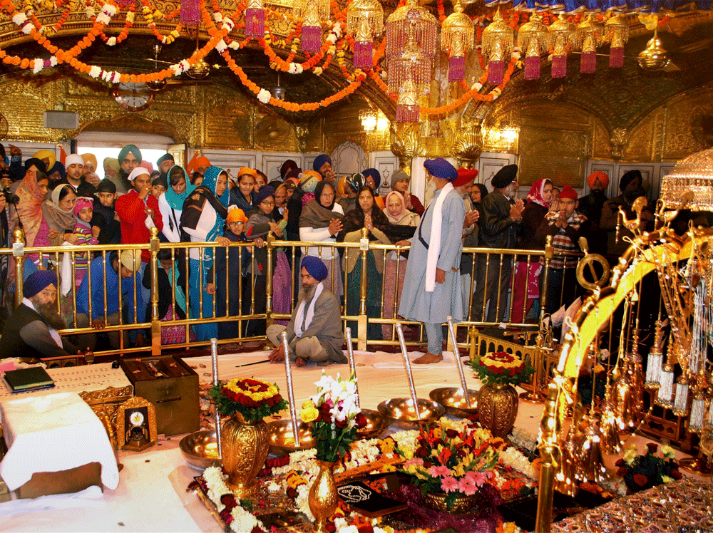Amritsar: Devotees paying obeisance and Sikh priest sits behind the Guru  Granth Sahib as a 'jalau', a show of Sikhism's symbolic items on the  occasion of Birth Anniversary of 10th Sikh Master Guru Gobind Singh ji  at Golden Temple, in Amritsar on T...