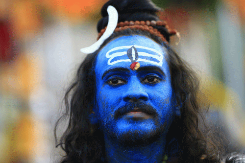 A devotee looks on, his face painted with blue powder, before a  pilgrimage to the sacred Batu Caves Temple during Thaipusam festival  outside Kuala Lumpur January 17, 2014. Thousands of Hindus, who comprise  over eight percent of the 29 million Mala...