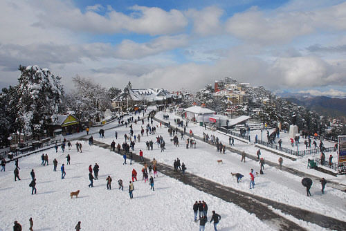People walk at historic Ridge Road after fresh snowfall in Shimla on Saturday. PTI Photo