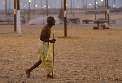A pilgrim walks at Sangam, the confluence of rivers Ganges, Yamuna and  mythical Saraswati river, during the annual traditional fair of 'Magh  Mela' in Allahabad, India, Friday, Feb. 21, 2014. Hundreds of thousands  of devout Hindus are expected to t...