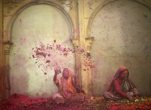 A widow throws flowers into the air during Holi celebrations organised by non-governmental organisation Sulabh International at a widows' ashram in Vrindavan in the northern Indian state of Uttar Pradesh March 14, 2014. Traditionally in Hindu culture...