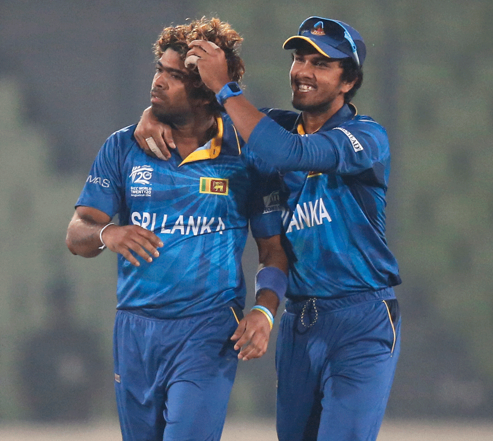 Sri Lanka's bowler Lasith Malinga, left, celebrates with captain Dinesh  Chandimal after the dismissal of India's batsman Virat Kohli during  their ICC Twenty20 Cricket World Cup warm up match in Dhaka, Bangladesh,  Monday March 17, 2014. (AP Photo/A...