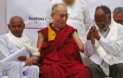 Exiled Tibetan spiritual leader, the Dalai Lama laughs as he holds the hands of leprosy-affected patients during his visit to a leprosy colony in New DelhiMarch 20, 2014. REUTERS