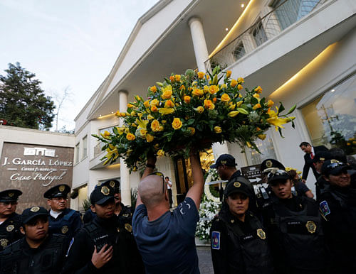 A man carries a flower wreath while passing through a line of police officers outside the funeral home where the body of Colombian Nobel Prize laureate Gabriel Garcia Marquez was taken to, in Mexico City April 17, 2014. Garcia Marquez, the Colombian ...