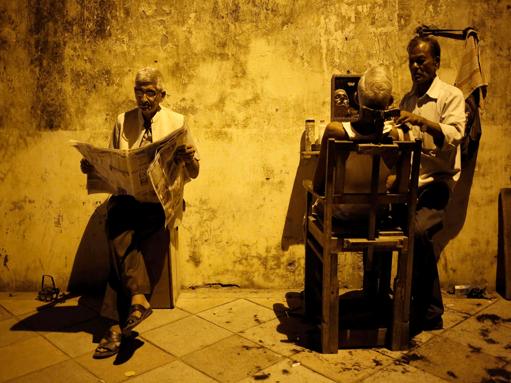  A man gets his shave done by a roadside barber as another reads a newspaper while waiting for his turn, in New Delhi August 20, 2014. Reuters photo