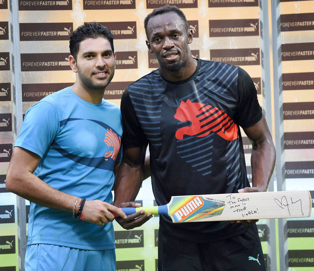 Bengaluru: Cricketer Yuvraj Singh presents a bat signed by him to  Olympic Gold Medalist sprinter Usain Bolt in the sidelines of a friendly  cricket match in Bengaluru on Tuesday. PTI Photo