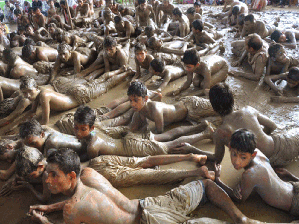 Children lying in mud during Buka Bhaona festival in Jorhat on Tuesday. PTI Photo