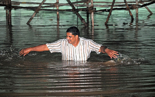 A man wade through hip-deep water that had inundated Kanteerava Stadium in Bangalore due to heavy rain on Thursday night. DH