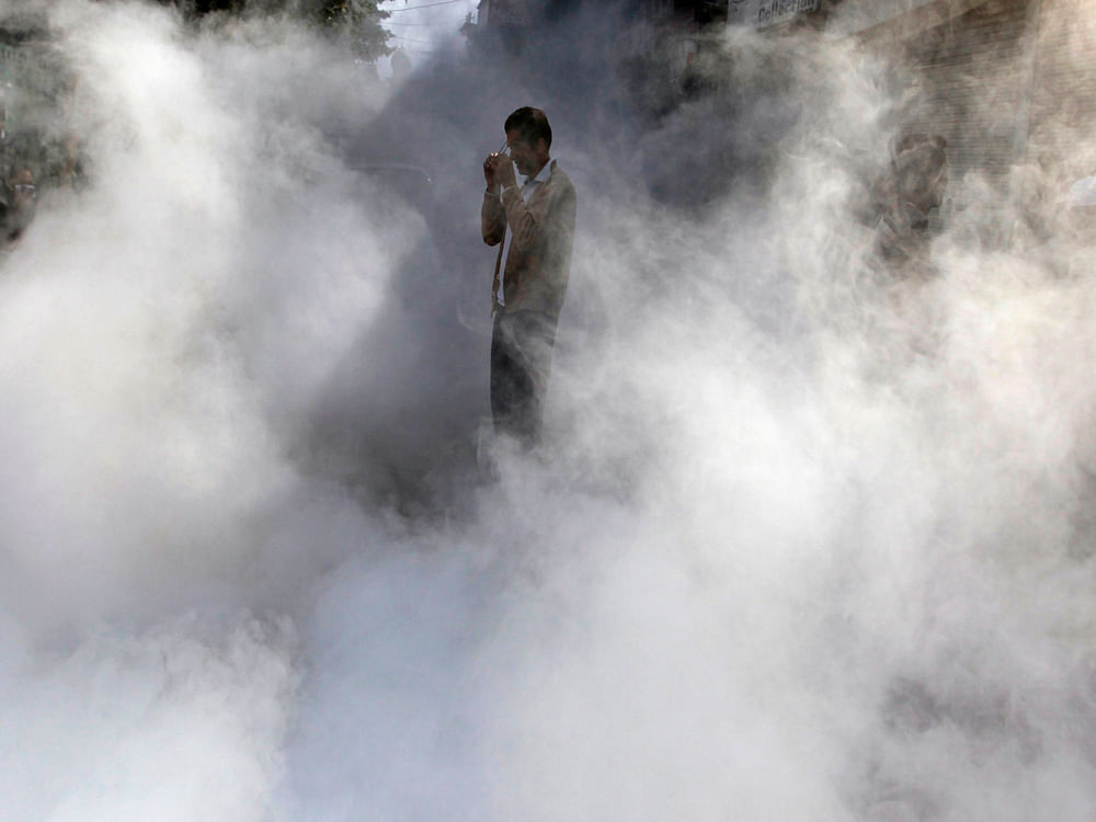 A man puts on his glasses as he stands in a street being fumigated by municipal workers in Srinagar October 13, 2014. REUTERS Image