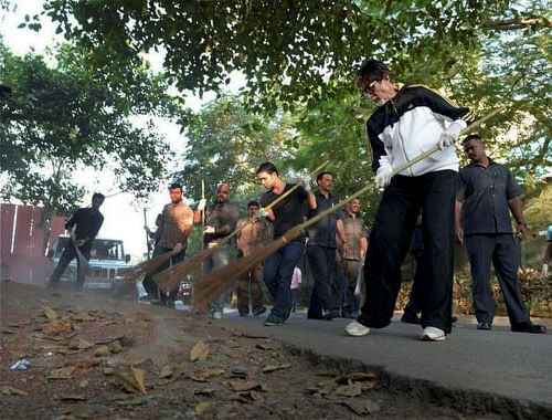 Mumbai: Bollywood megastar Amitabh Bachchan sweeps in a stree during a cleanliness drive as a part of 'Swachh Bharat Abhiyan' in Mumbai on Wednesday. PTI Photo / twitter@SrBachchan