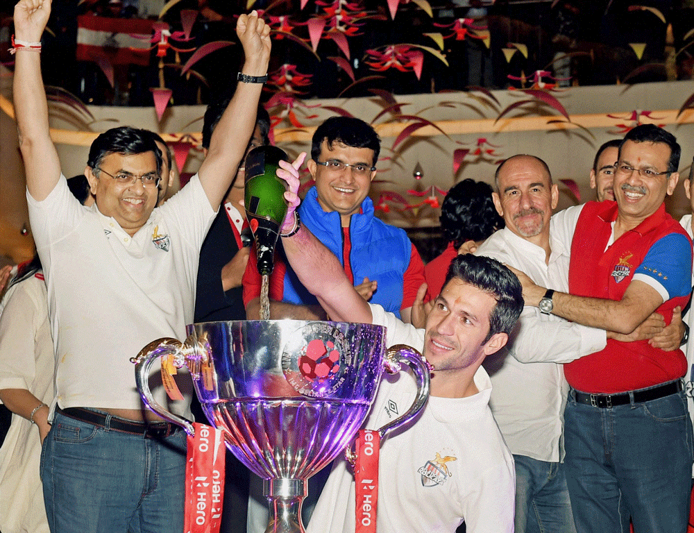 A Player Atletico De Kolkata footballer pours champagne on the Trophy during their felicitation program after winning 1st Indian Super League in Kolkata on Sunday. Team Co-owners, Utasav Parekh,Sourav Ganguly,Sanjiv Goenka and Head Coach of the team ...
