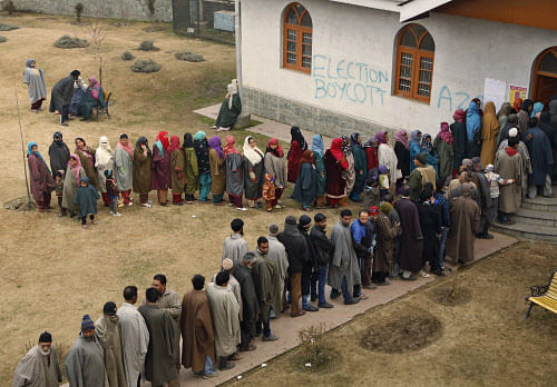 Kashmiris stand in queue to cast their votes outside a polling station, the wall of which has a graffiti calling for election boycott during the fourth phase polling of the Jammu and Kashmir state elections in Srinagar. J&K heads for a hung assembly ...