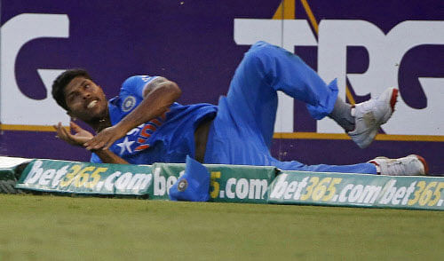 India's Umesh Yadav crashes on the boundary as he attempts to prevent four runs by England's batsman Ian Bell during his One Day International (ODI) tri-series cricket match in Brisbane, January 20, 2015. REUTERS