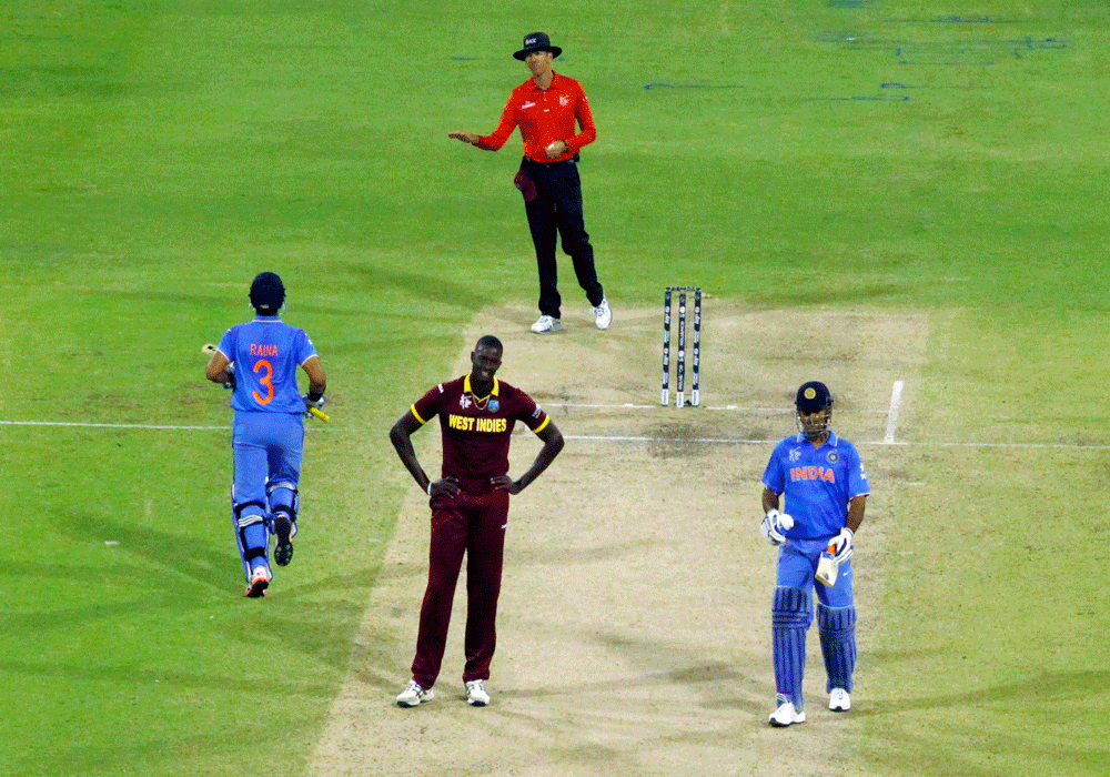 West Indies captain Jason Holder (C) reacts as India's Suresh Raina (L) scores four runs alongside MS Dhoni during their Cricket World Cup win over the West Indies in Perth, March 6, 2015. REUTERS