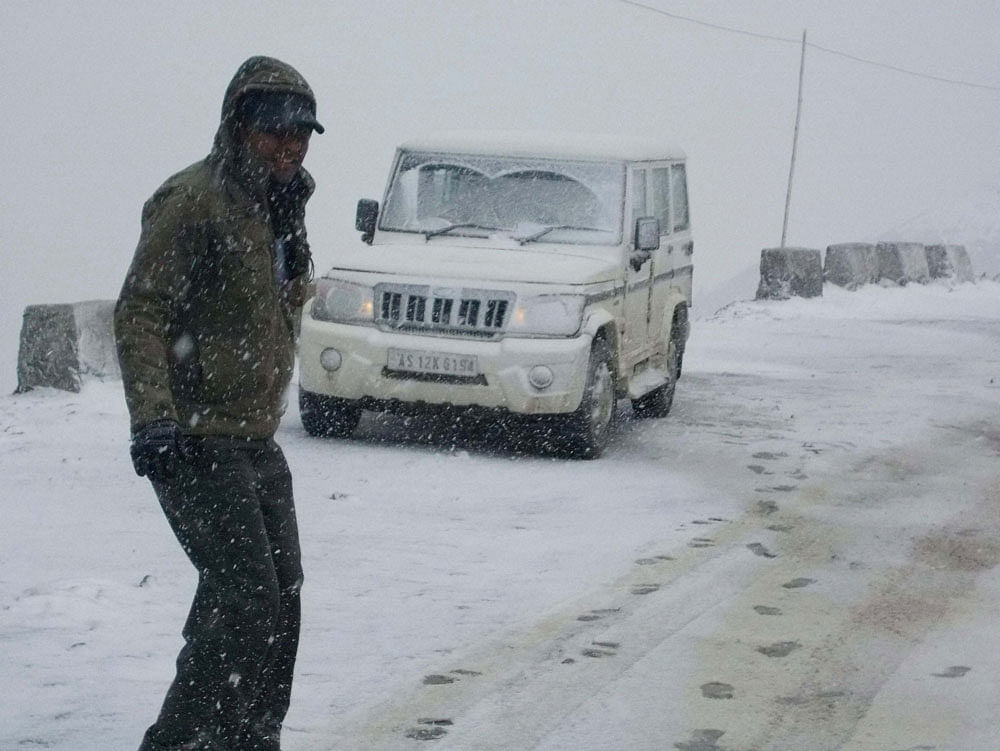 A tourist enjoys snowfall in Tezpur on Monday. PTI Photo