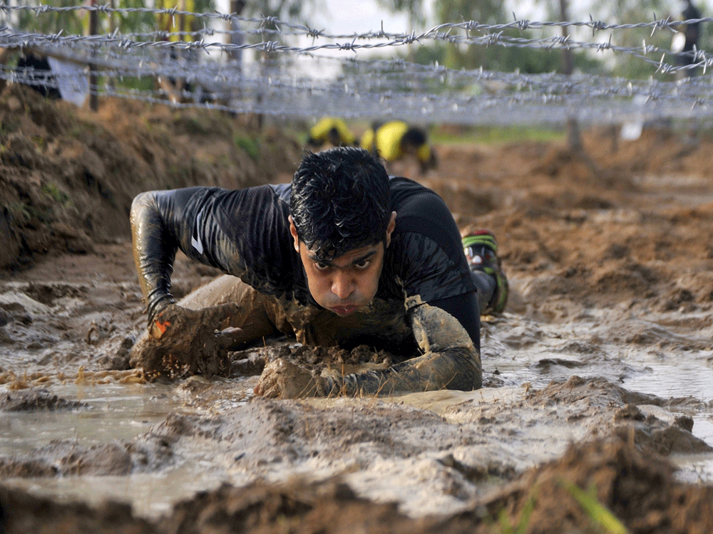 A competitor crawls beneath barbed wire during the Alpha League Races in Bengaluru, India, June 7, 2015. Around 2000 people participated in the 5-km endurance race with 20 different obstacles, organisers said. Reuters Photo.