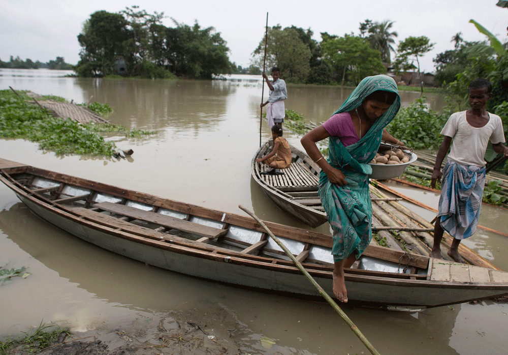 A flood affected woman gets down from a boat at Paka Betbari Pam village about 130 kilometers (about 81 miles) west of Gauhati, India, Tuesday, June 9, 2015. According to local news reports, the monsoon rains have caused floods in several districts o...