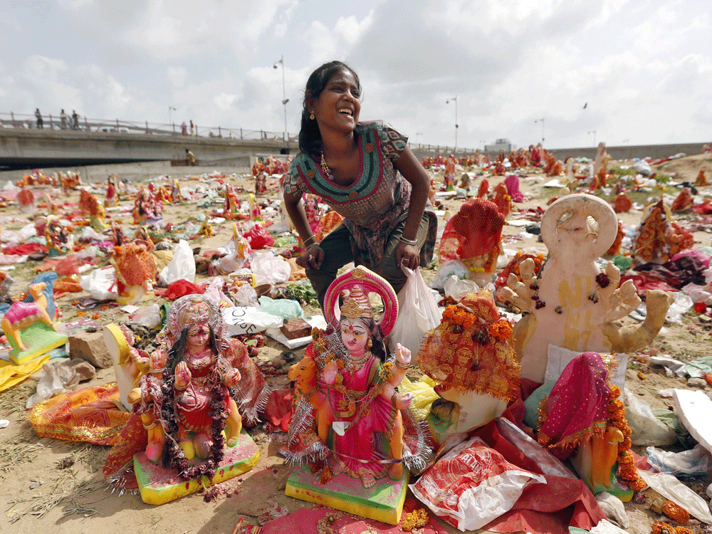 A woman collects idol of Hindu goddess Dashama left by devotees on the banks of the river Sabarmati on 10th and final day of Dashama festival in Ahmedabad. Reuters Photo.