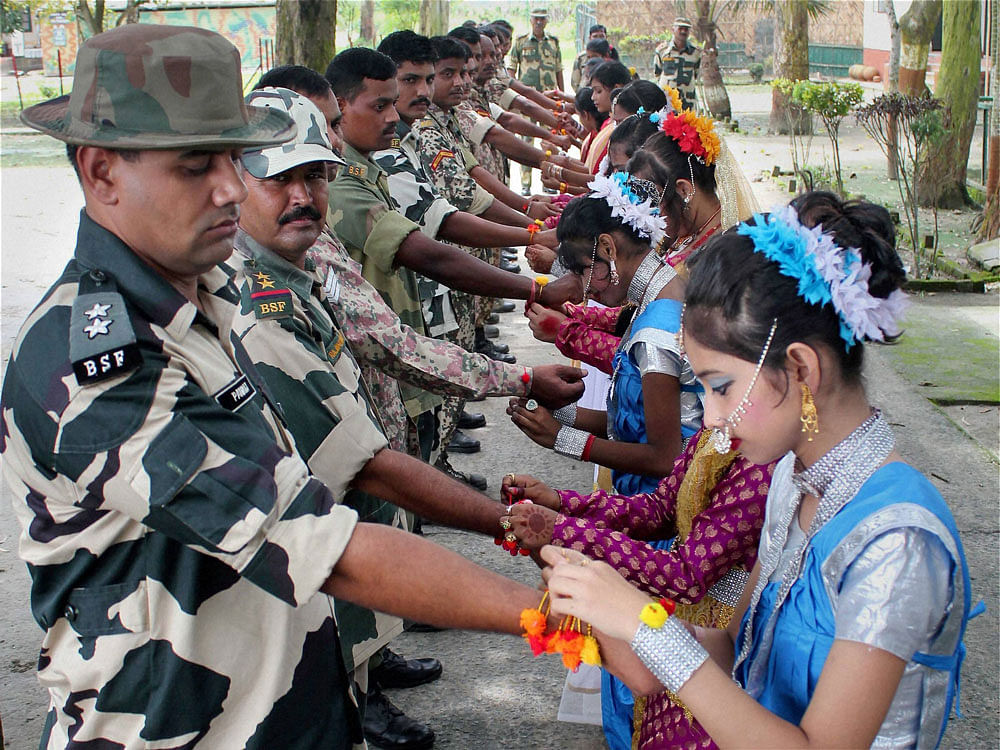 School girls tying Rakhi on the wrists of BSF personnel during celebrations of Raksha Bandhan festival at Indo-Bangladesh international border at Hili near Balurghat in South Dinajpur district of West Bengal on Saturday. PTI Photo