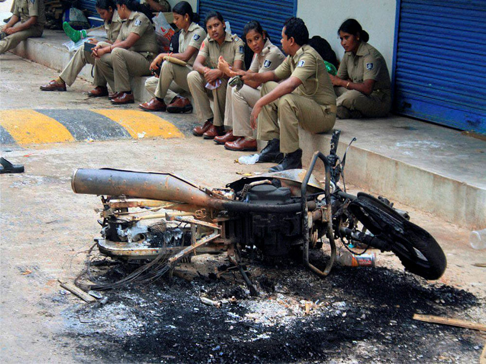 Police personnel sitting near the charred remains of a motorcyle near  the violence-hit Trahi Achyuta Ashram on the outskirts of Bhubaneswar on  Monday. PTI Photo