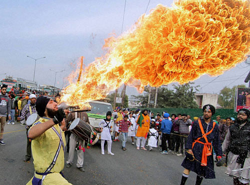 A Sikh devotee performs with fire during a religious procession ahead of the birth anniversary of Guru Nanak Dev in Jammu on Monday. PTI Photo