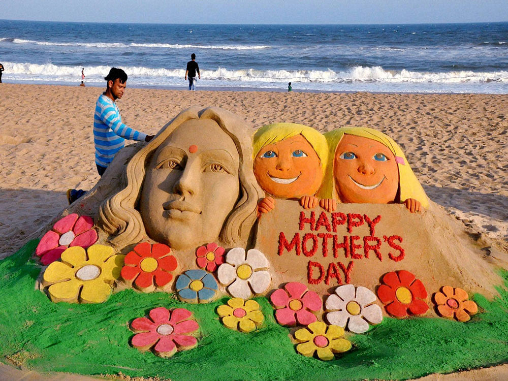  Sand artist Manas Kumar Sahoo create a sand sculpture on eve of Mother’s day in Puri on Saturday. PTI Photo.