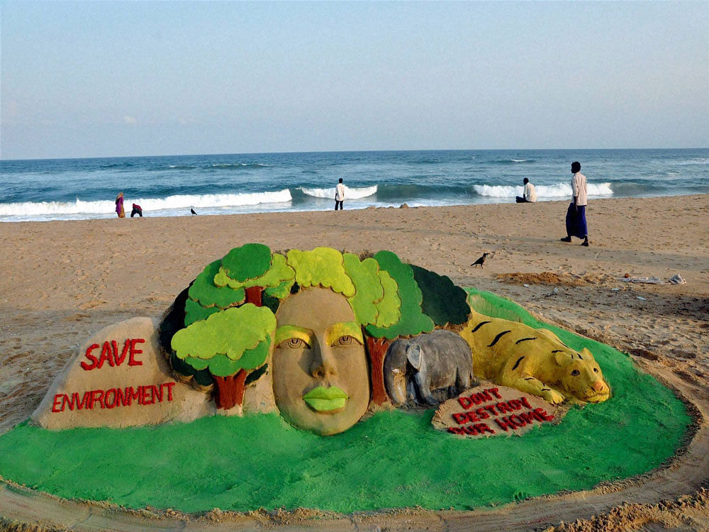 Sand artist Manas Sahoo creates a sand sculpture on the occasion of world Environment Day in Puri on Sunday.PTI Photo.