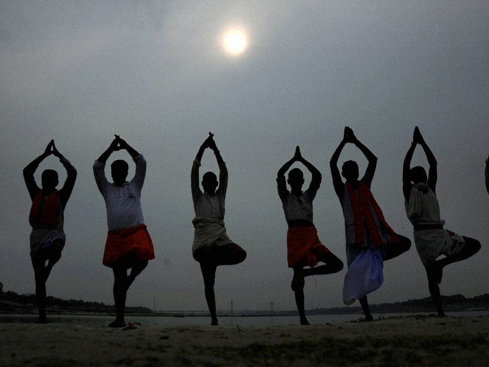 Local priests performing Yoga on the eve of International Yoga day in Allahabad on Monday. PTI Photo