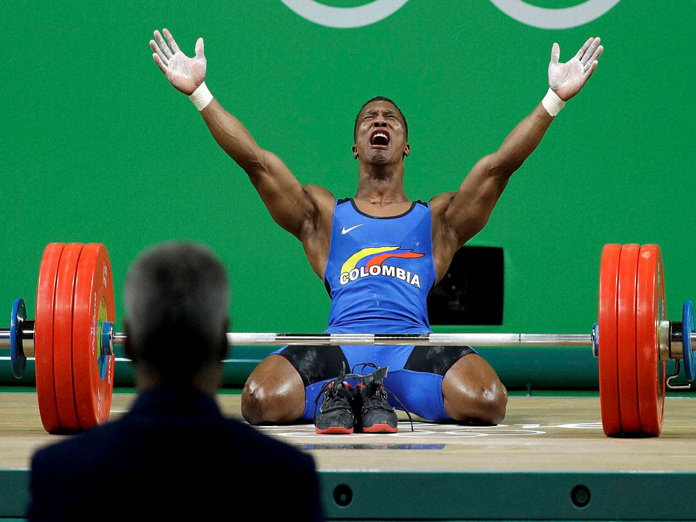 Oscar Albeiro Figueroa Mosquera, of Colombia, celebrates after winning the gold medal in the men's 62kg weightlifting competition at the 2016 Summer Olympics in Rio de Janeiro, Brazil, Monday, Aug. 8, 2016. A judge looks on in the foreground. AP/PTI ...