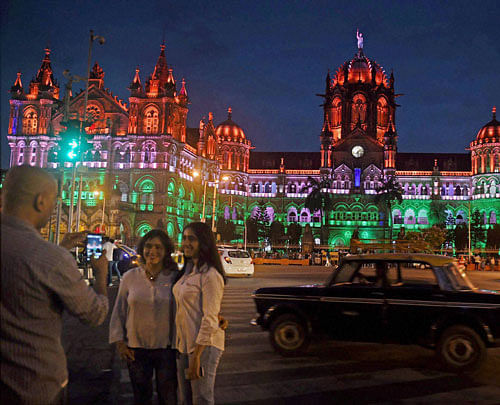  People take pictures in front of Chatrapati Shivaji terminus as it was lit up in tri colours on the eve of the Independence day in Mumbai on Sunday. PTI Photo