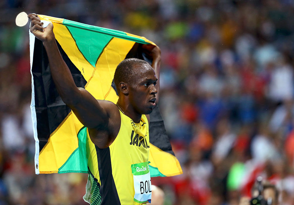 Usain Bolt (JAM) of Jamaica holds his national flag after winning the race. REUTERS