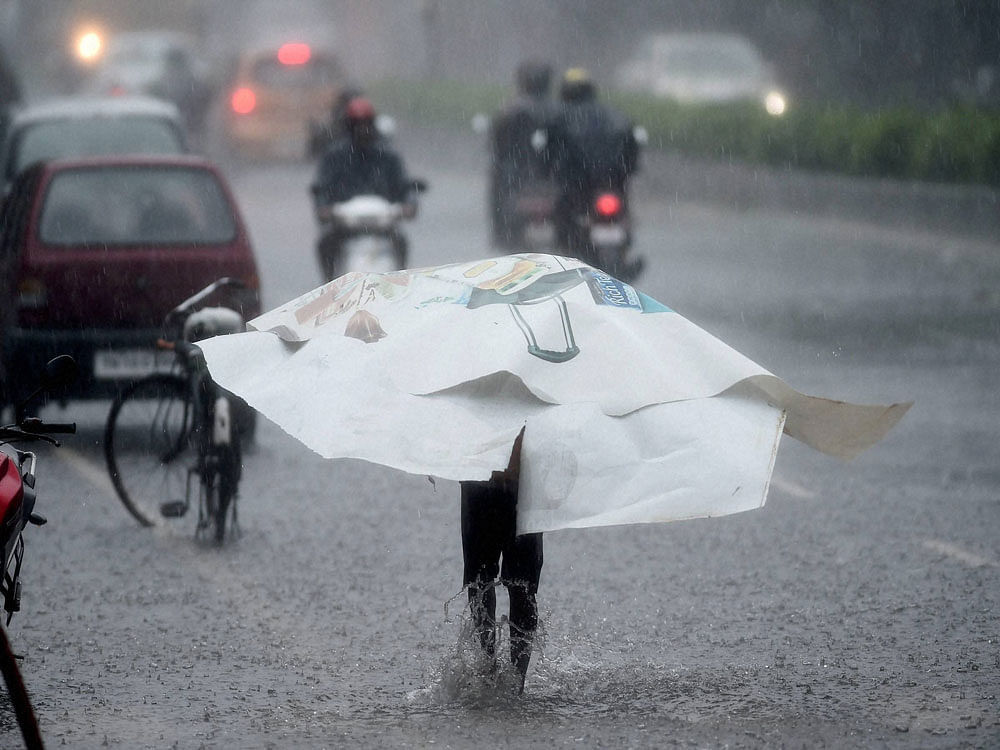 A person wades through road filled with water during heavy rainfall as cyclone Vardah made landfall near Chennai coast on Monday. PTI Photo