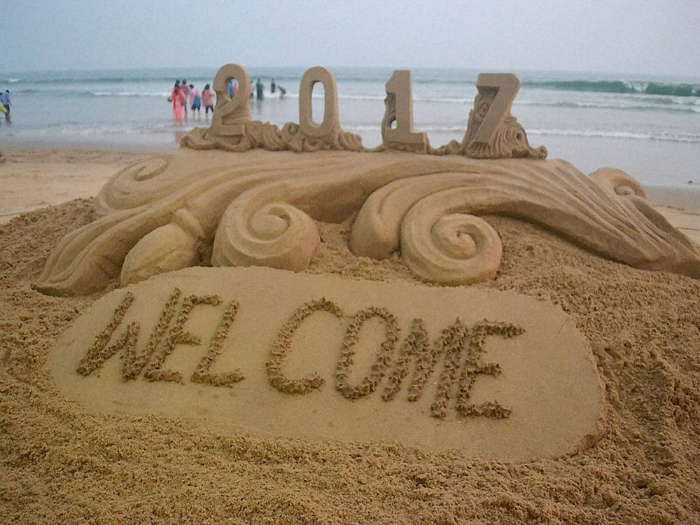 Sand artist Sudarsan Pattnaik has created a sand sculpture with message of New year 2017 greetings at Puri beach of Odhisa on Saturday. PTI Photo