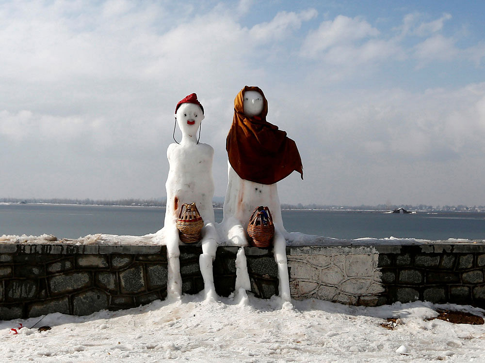 A snow man and a snow woman with 'Kangris', traditional fire pots, are installed on the banks of Dal Lake in Srinagar. Reuters