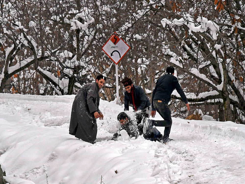 Boys playing with snow after heavy snowfall on the outskirts of Srinagar on Monday. PTI Photo