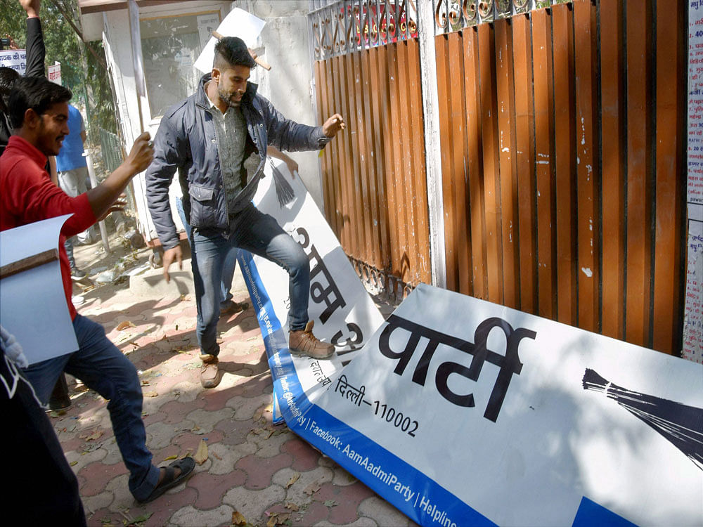 AAP workers smash a hoarding as they protest outside the party office over alleged discrepencies in MCD tickets distribution in New Delhi on Sunday. PTI Photo