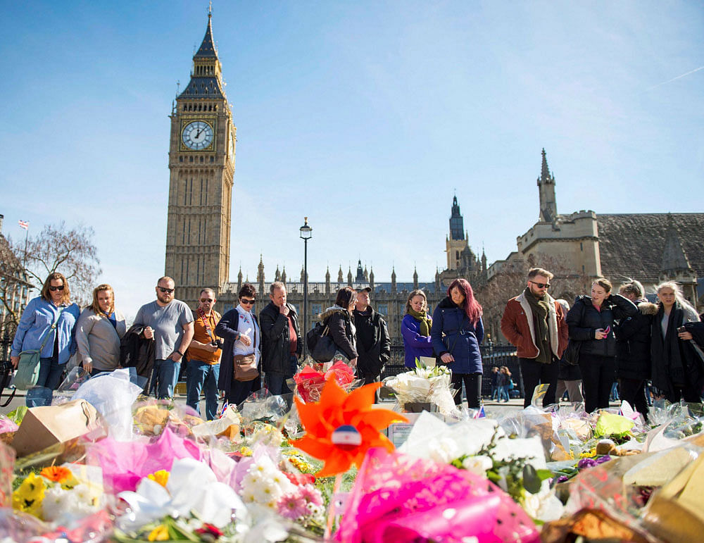 People look at floral tributes in Parliament Square, London, Sunday, March 26, 2017, laid out for the victims of the Westminster attack on Wednesday. Khalid Masood killed four people and left more than two dozen hospitalized, including some with what...