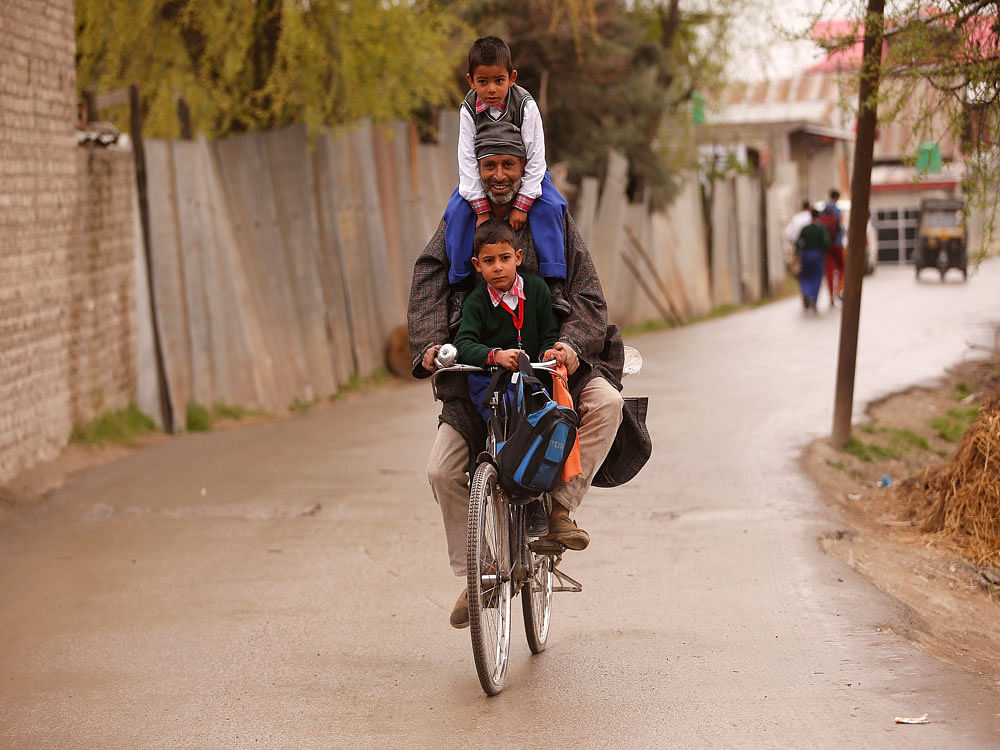 A man carries schoolchildren on his bicycle on a road in Srinagar, India. Reuters Photo