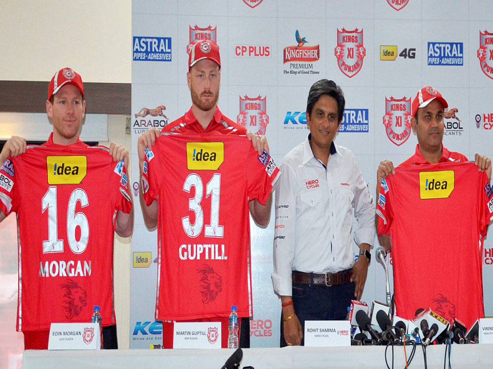 Kings XI Punjab players Eoin Morgan, Martin Guptil and Virendra Sehwag at the launch of their team jersey in Indore on Tuesday. PTI Photo