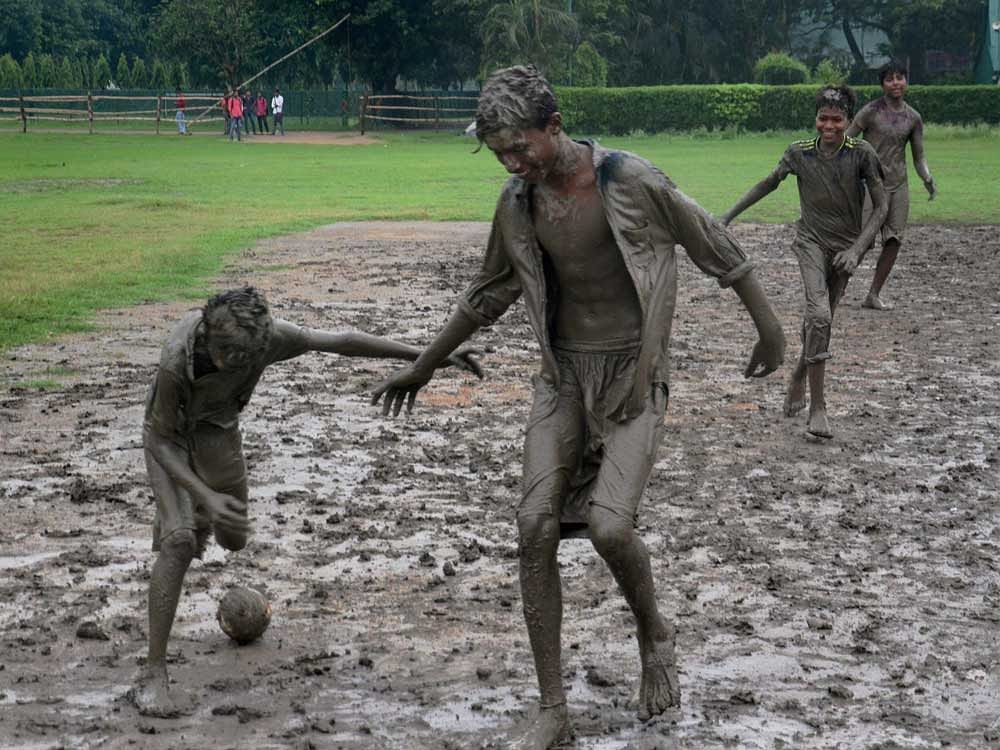 Children play football in mud after rainfall in Kolkata on Friday. PTI