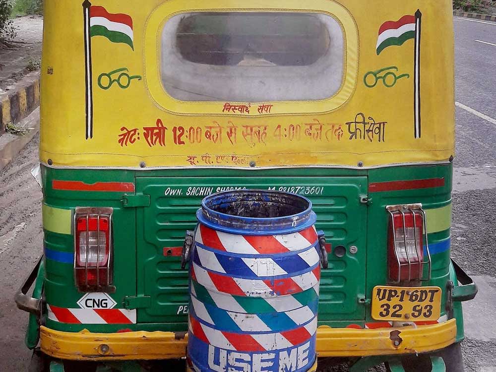 An auto rickshaw is spreading the message of cleanliness with a dustbin at it , in Delhi-NCR.