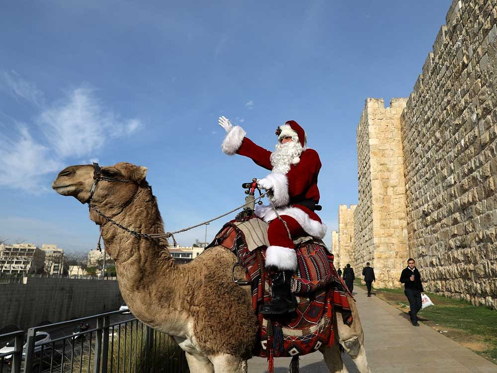 Israeli-Arab Issa Kassissieh rides a camel wearing a Santa Claus costume during the annual Christmas tree distribution by the Jerusalem municipality in Jerusalem's Old City December 21, 2017. 
