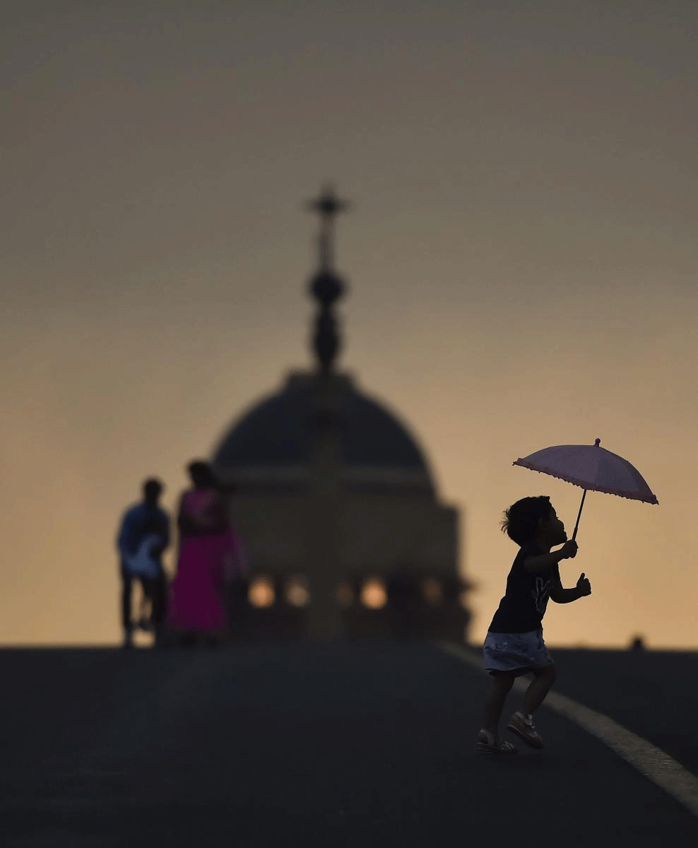 People are seen silhouetted as they enjoy the pleasant weather before after rains, at Raisina Hills in New Delhi on Sunday. PTI Photo 