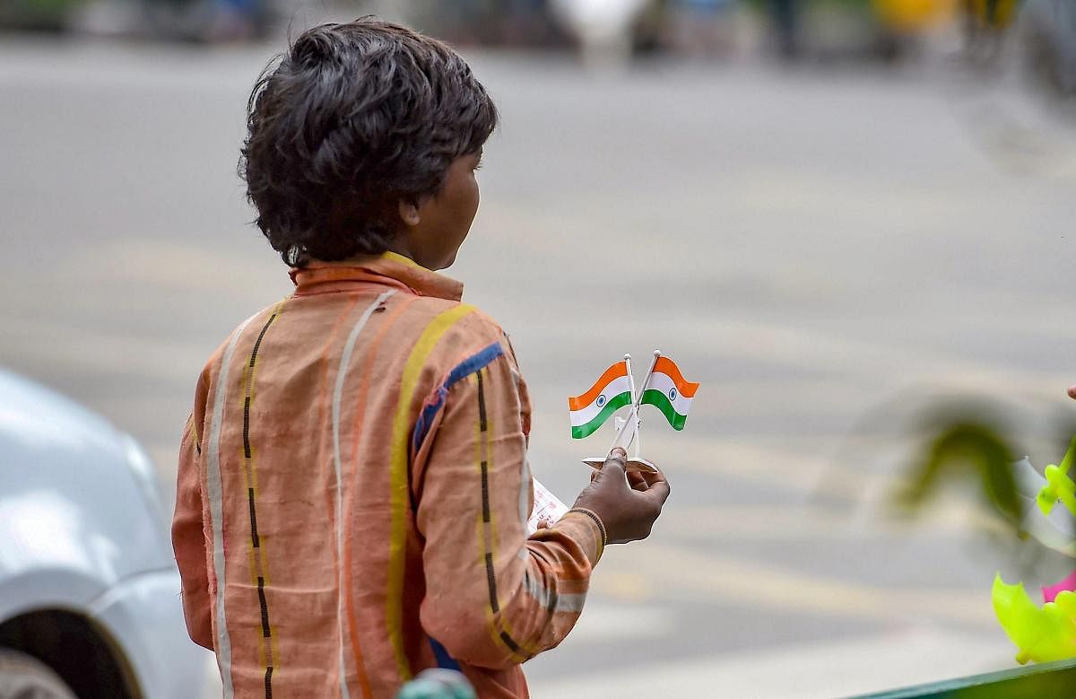 A child selling the tricolour waits for customers at a roadside during the 72nd Independence day celebration at Manesk Shaw parade ground in Bengaluru on Wednesday, Aug 15, 2018. (PTI Photo)